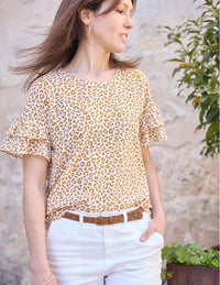 Woman wearing the Idole Blouse sewing pattern from Atelier Scämmit on The Fold Line. A top pattern made in cotton, viscose, or knit fabric, featuring a round neckline and grown-on short sleeves with ruffles.