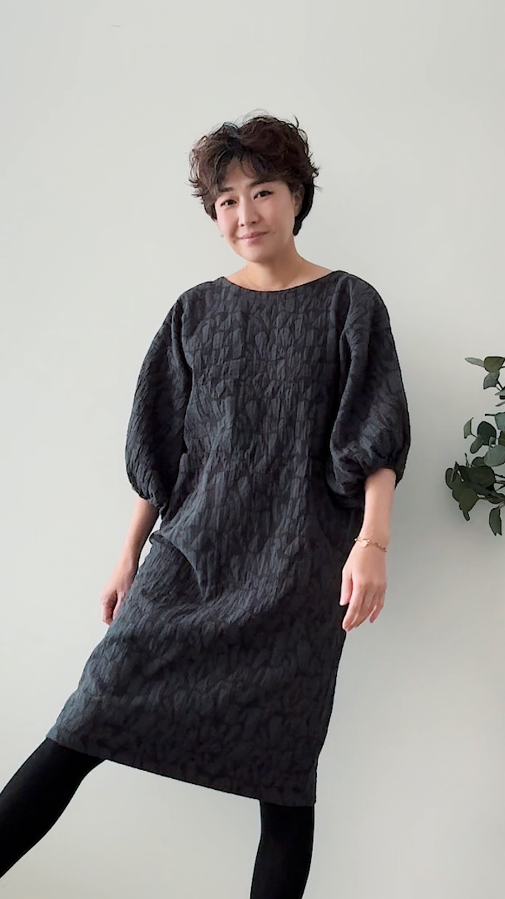 Woman wearing the Infit Dress sewing pattern from Sewing Therapy on The Fold Line. A dress pattern made in cotton, linen, jersey, chambray or denim, rayon, flannel or wool fabric, featuring an oversized silhouette, round neckline, voluminous mid-length sleeves, and knee length.