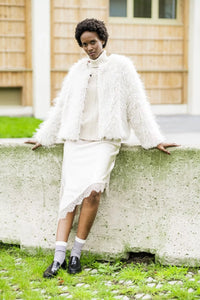 Woman wearing the Inga Jacket sewing pattern from Fibre Mood on The Fold Line. A lined jacket pattern made in faux fur, teddy, bouclé, or faux shearling fabric, featuring a straight cut and hook and eye closure.