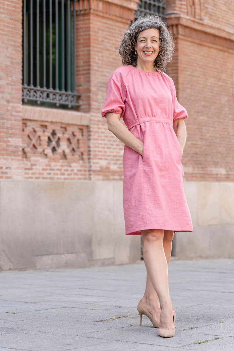 Woman wearing the Isola Dress sewing pattern from Liesl + Co on The Fold Line. A knee-length dress pattern made in cotton voile, lawn, shirting, linen, lightweight crepe, or rayon fabric, featuring a round neck with gathers, princess seams, elbow-length raglan sleeves, and front pockets. 