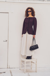 Woman wearing the Jacoba Blazer sewing pattern from Fibre Mood on The Fold Line. A lined jacket pattern made in light denim, cotton twill, gabardine, cotton satin, or light canvas fabric, featuring a wide neckline, concealed button closure, grown-on balloon sleeves, and welt pockets. 