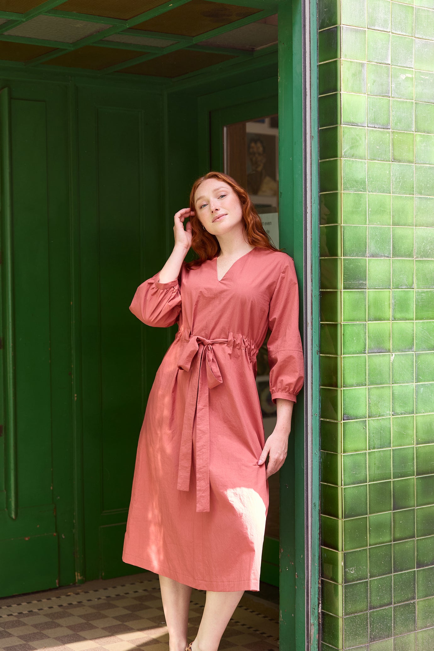 Woman wearing the Jamie Dress sewing pattern from Atelier Jupe on The Fold Line. A dress pattern made in viscose, cotton, tencel, double gauze, or linen fabric, featuring a V-neck, tie belt, 3/4 sleeves, and below knee length.