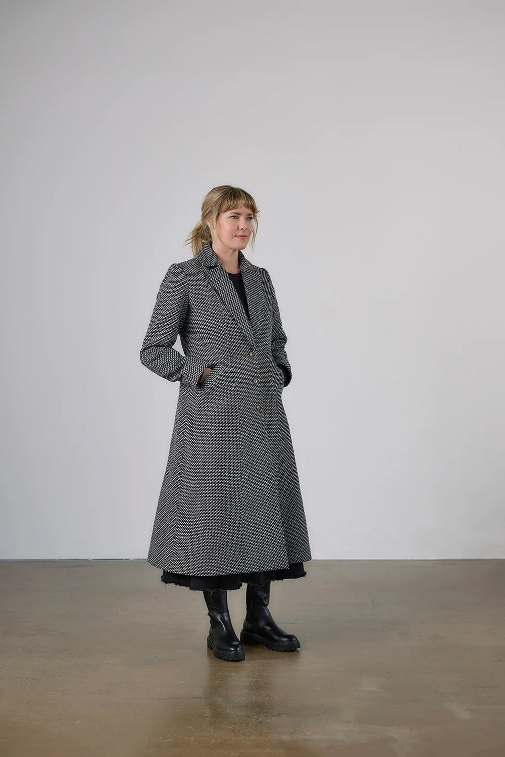 Woman wearing the Janzi Coat sewing pattern from Elbe Textiles on The Fold Line. A fully lined coat pattern made in tweed, bouclé, boiled wool, wool felt, or wool blend fabric, featuring a collar and lapel, princess seams, button front, two-piece sleeves, welt pockets, and calf length.