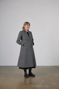 Woman wearing the Janzi Coat sewing pattern from Elbe Textiles on The Fold Line. A fully lined coat pattern made in tweed, bouclé, boiled wool, wool felt, or wool blend fabric, featuring a collar and lapel, princess seams, button front, two-piece sleeves, welt pockets, and calf length.