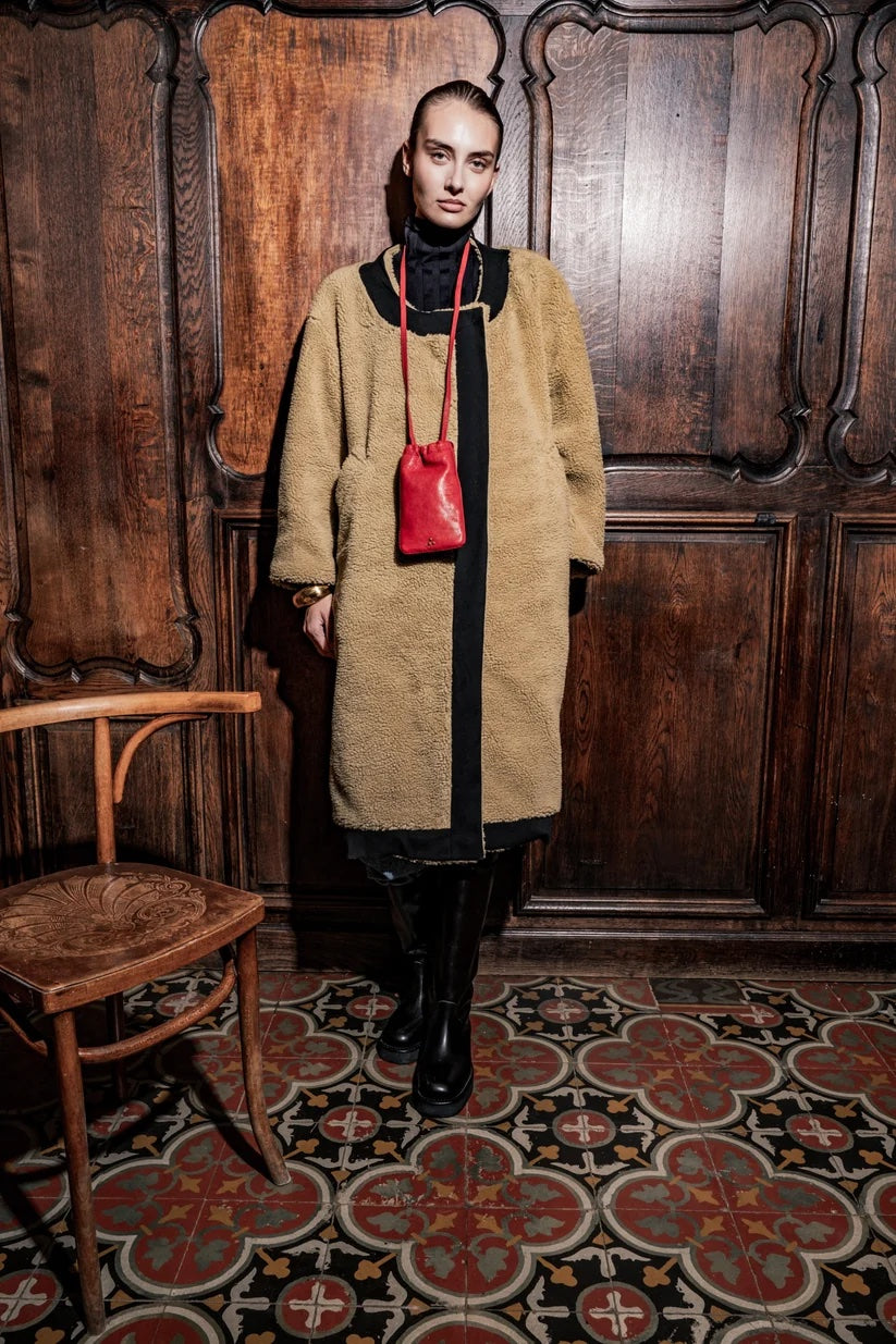 Woman wearing the Jerom Coat sewing pattern from Fibre Mood on The Fold Line. A coat pattern made in wool, jacquard, coating, or teddy fabric, featuring a straight cut, round neckline, pockets, and contrast edges.