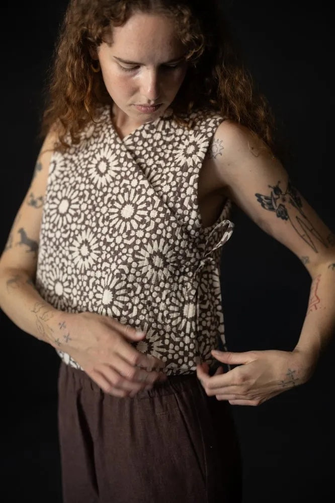 Woman wearing the Joa Top sewing pattern from Merchant & Mills on The Fold Line. A sleeveless top pattern made in linen, cotton, denim, or pre-quilted fabric, featuring a V-neck and wrap front with side ties.