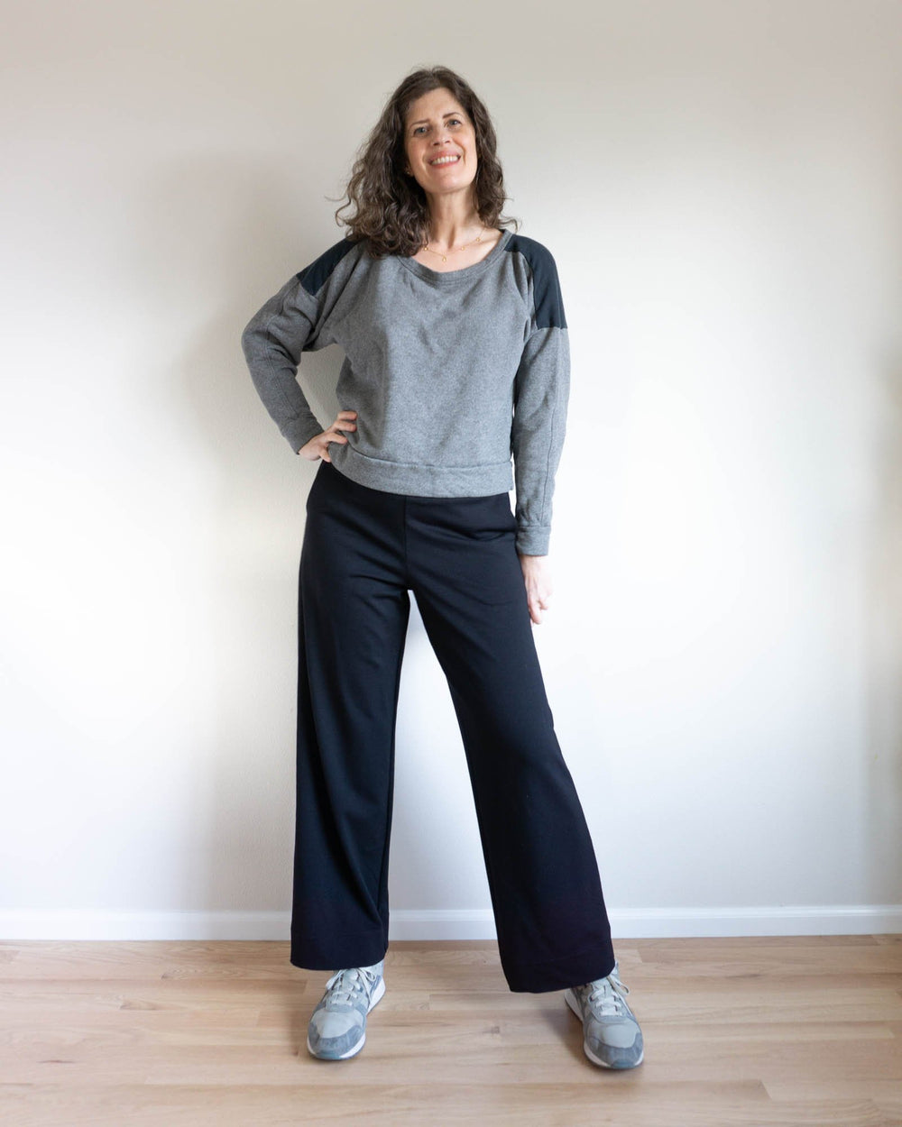 Woman wearing the Jodi Knit Pants sewing pattern from Sew DIY on The Fold Line. A wide leg pants pattern made in knit fabric, featuring a medium rise, elastic waistband, angled side seam pockets, and ankle length.