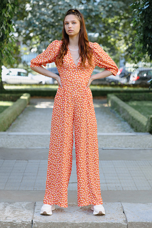 Woman wearing the Jolene Jumpsuit sewing pattern from JULIANA MARTEJEVS on The Fold Line. A jumpsuit pattern made in viscose, linen, or cotton fabric, featuring a deep V-neckline, gathers under the bust, mid-length puff sleeves, and wide legs.