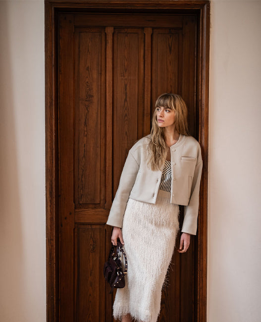 Woman wearing the Judith Jacket sewing pattern from Fibre Mood on The Fold Line. A lined bomber style jacket pattern made in wool, sweater fabric, punta di Roma, nylon, leather, or quilted fabric, featuring a boxy fit, button fastening, and welt pockets.