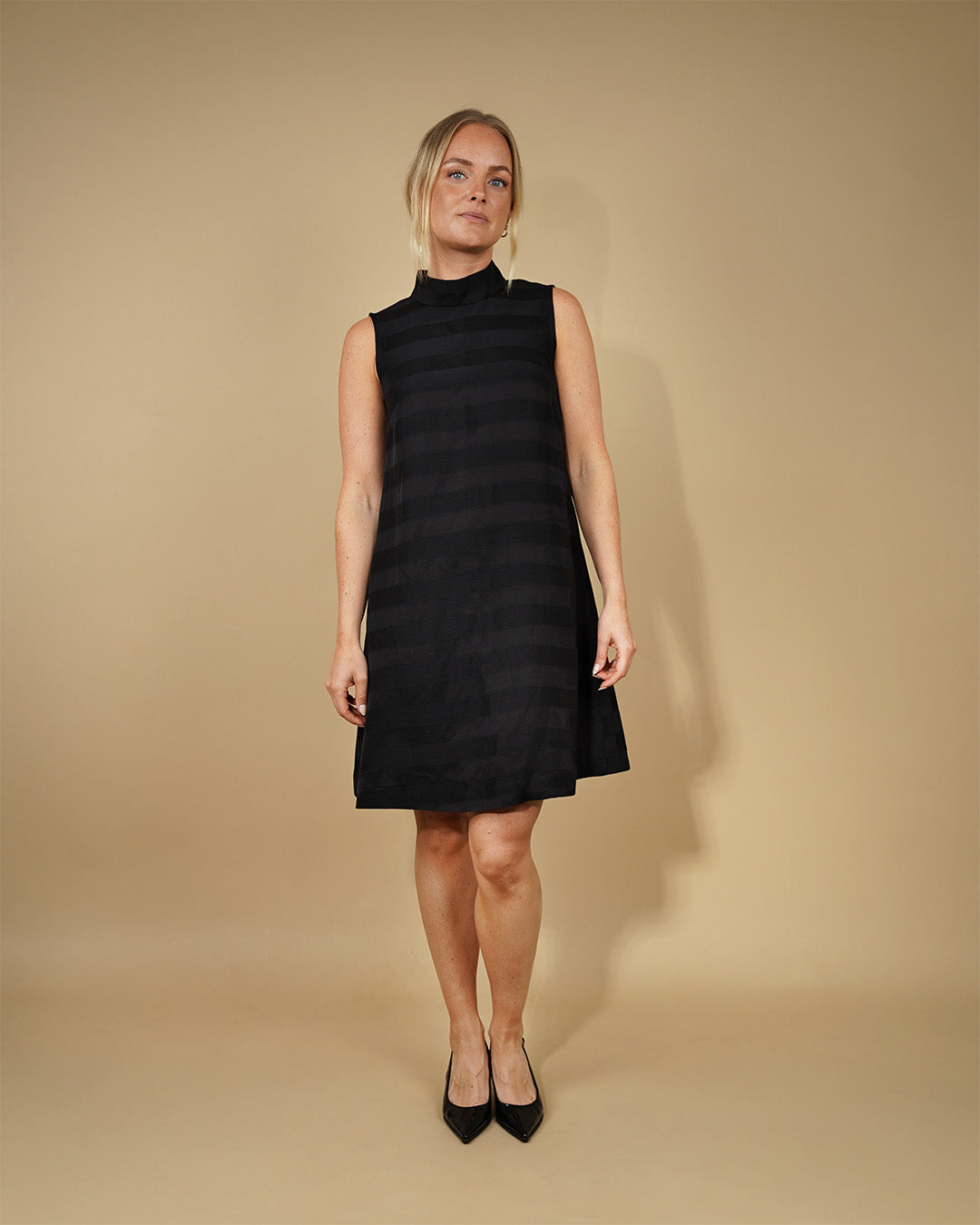 Woman wearing the June Dress sewing pattern from Wardrobe by Me on The Fold Line. A sleeveless dress pattern made in denim, cotton twill, linen, chambray, viscose-linen blends, or crinkled cotton (seersucker) fabric, featuring a relaxed A-line silhouette, standing collar, back keyhole opening, and knee length.