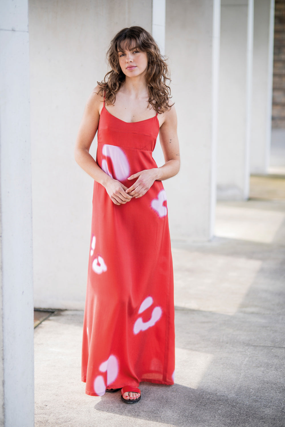 Woman wearing the June Dress sewing pattern from Fibre Mood on The Fold Line. A dress pattern made in poplin, linen, supple twill, double gauze, chambray, or seersucker fabric, featuring spaghetti straps, an empire waist, bow and elastic at the back, and maxi length.