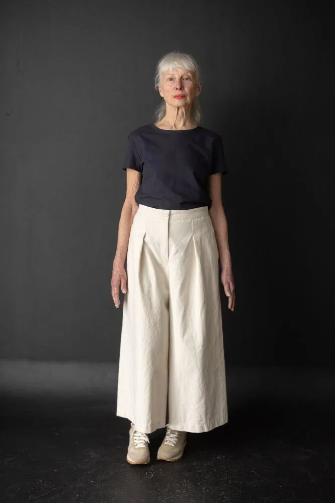 Woman wearing the Juno Culottes sewing pattern from Merchant & Mills on The Fold Line. A trousers pattern made in mid-weight cotton canvas, sanded twill, corduroy, light-medium weight woollens, denim, linen, or tencel/linen fabric, featuring a fly front, front pleats, in-seam pockets, and an elasticated back waistband. 