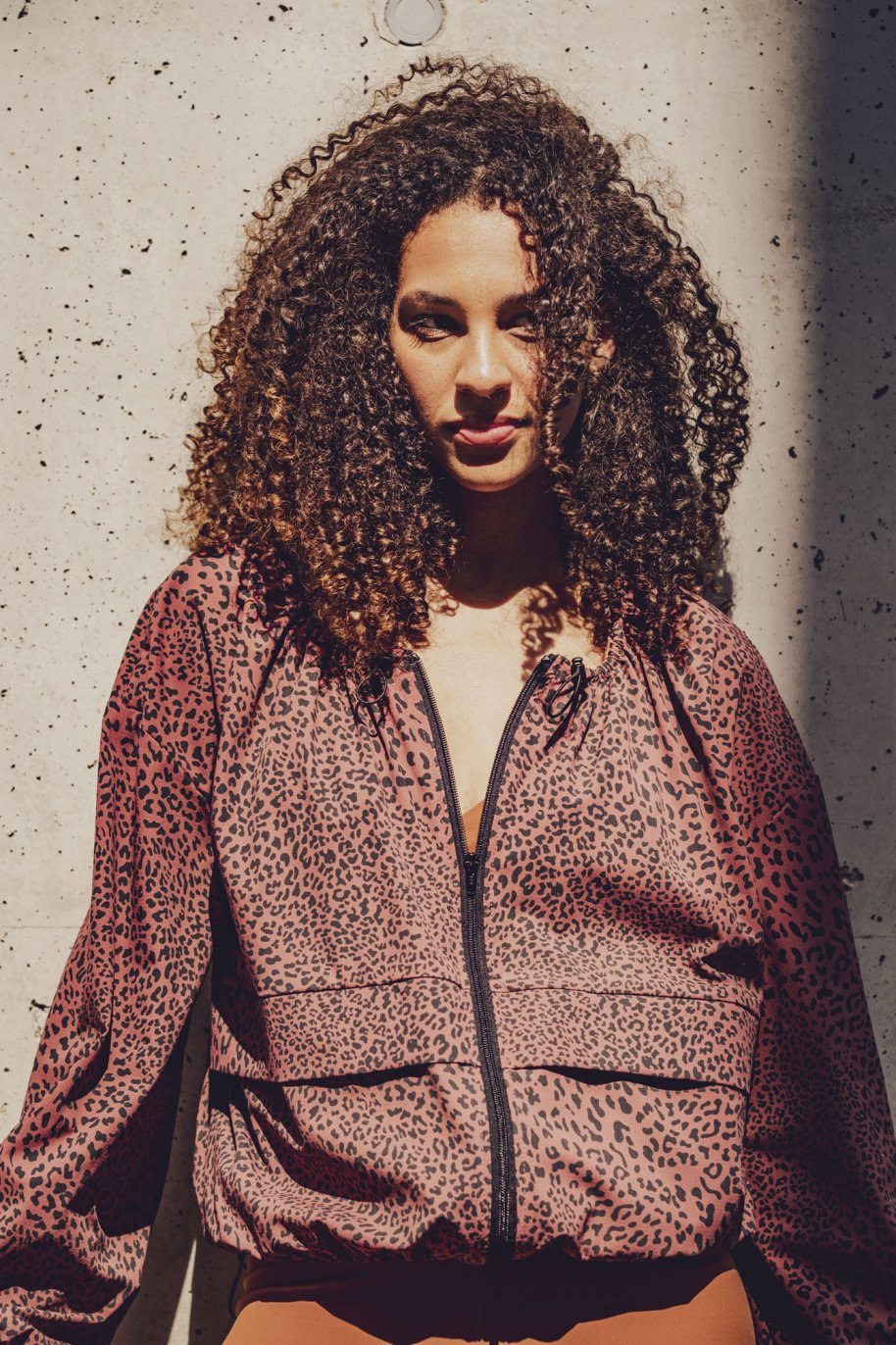 Woman wearing the Juno Jacket sewing pattern from Fibre Mood on The Fold Line. A jacket pattern made in nylon or polyester taffeta, coated cotton, laminated fabric, TPU, or vinyl fabric, featuring a relaxed fit, zipper front, long sleeves, and puff effect created by adjustable drawstrings.
