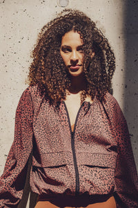 Woman wearing the Juno Jacket sewing pattern from Fibre Mood on The Fold Line. A jacket pattern made in nylon or polyester taffeta, coated cotton, laminated fabric, TPU, or vinyl fabric, featuring a relaxed fit, zipper front, long sleeves, and puff effect created by adjustable drawstrings.