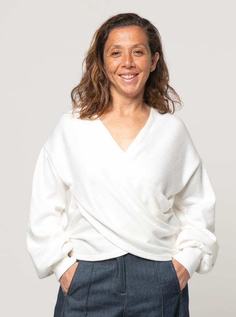 Woman wearing the Kira Knit Top sewing pattern from Style Arc on The Fold Line. A top pattern made in jersey, interlock, or stretch knit fabric, featuring a relaxed fit, draped style crossover front, V-neck, and long full sleeves gathered into cuffs.