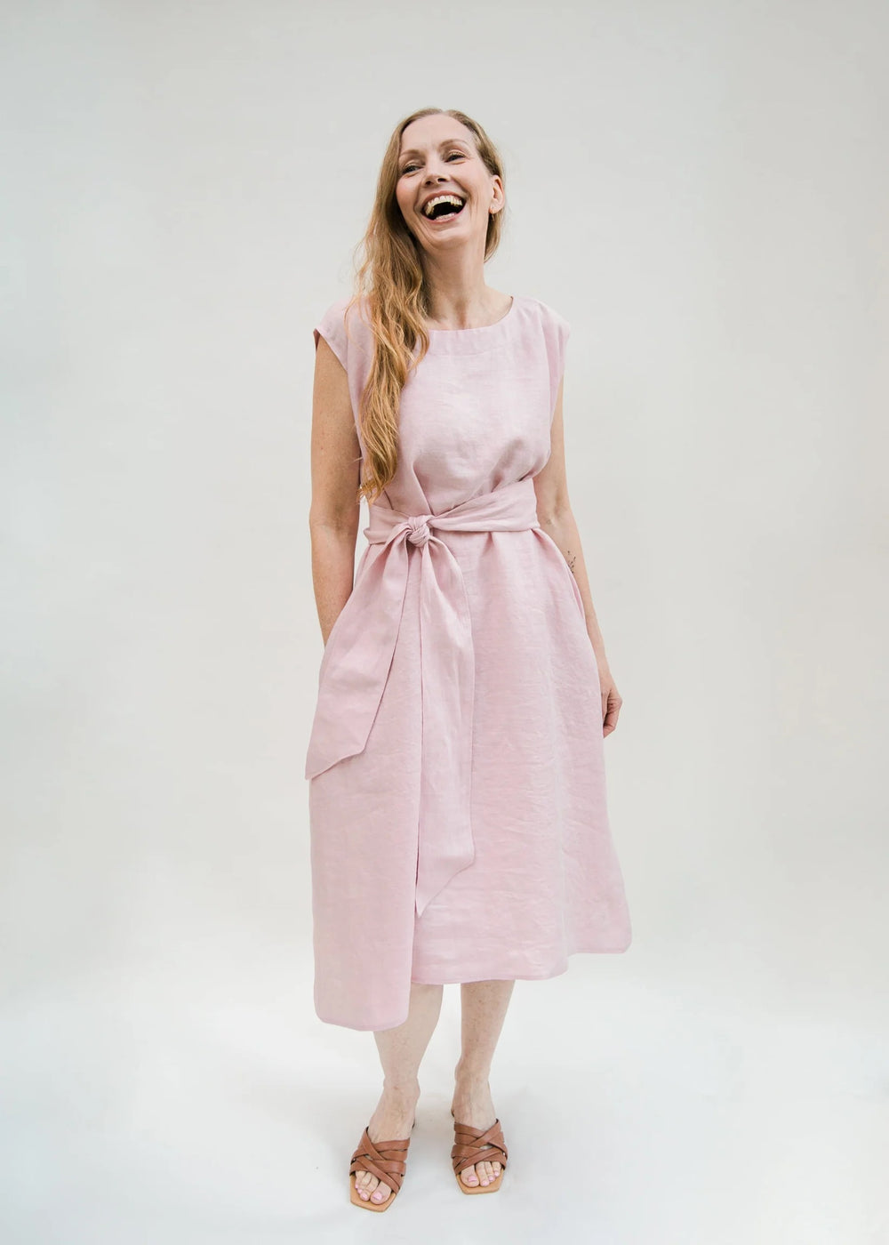 Woman wearing the Kite Dress sewing pattern from Cris Wood Sews on The Fold Line. A dress pattern made in linen, rayon, silk, viscose blend, or lightweight cotton fabric, featuring a relaxed fit, A-line shape, round neckline, grown-on short sleeves, wide sash belt, and midi length.
