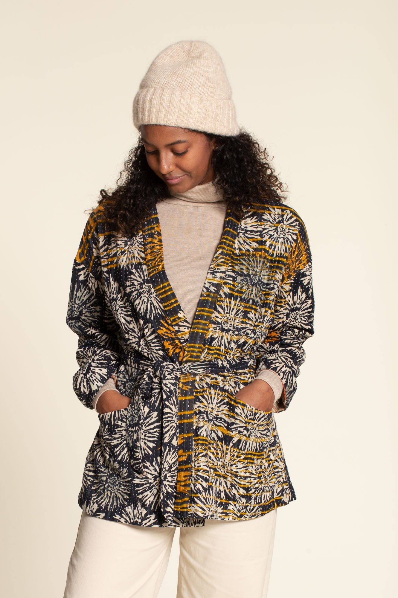 Woman wearing the Komi Jacket sewing pattern from Wardrobe by Me on The Fold Line. An unlined jacket pattern made in cotton, linen, double gauze, quilted, or jersey fabric, featuring a wrap front with a belt, dropped shoulders, and deep pockets.