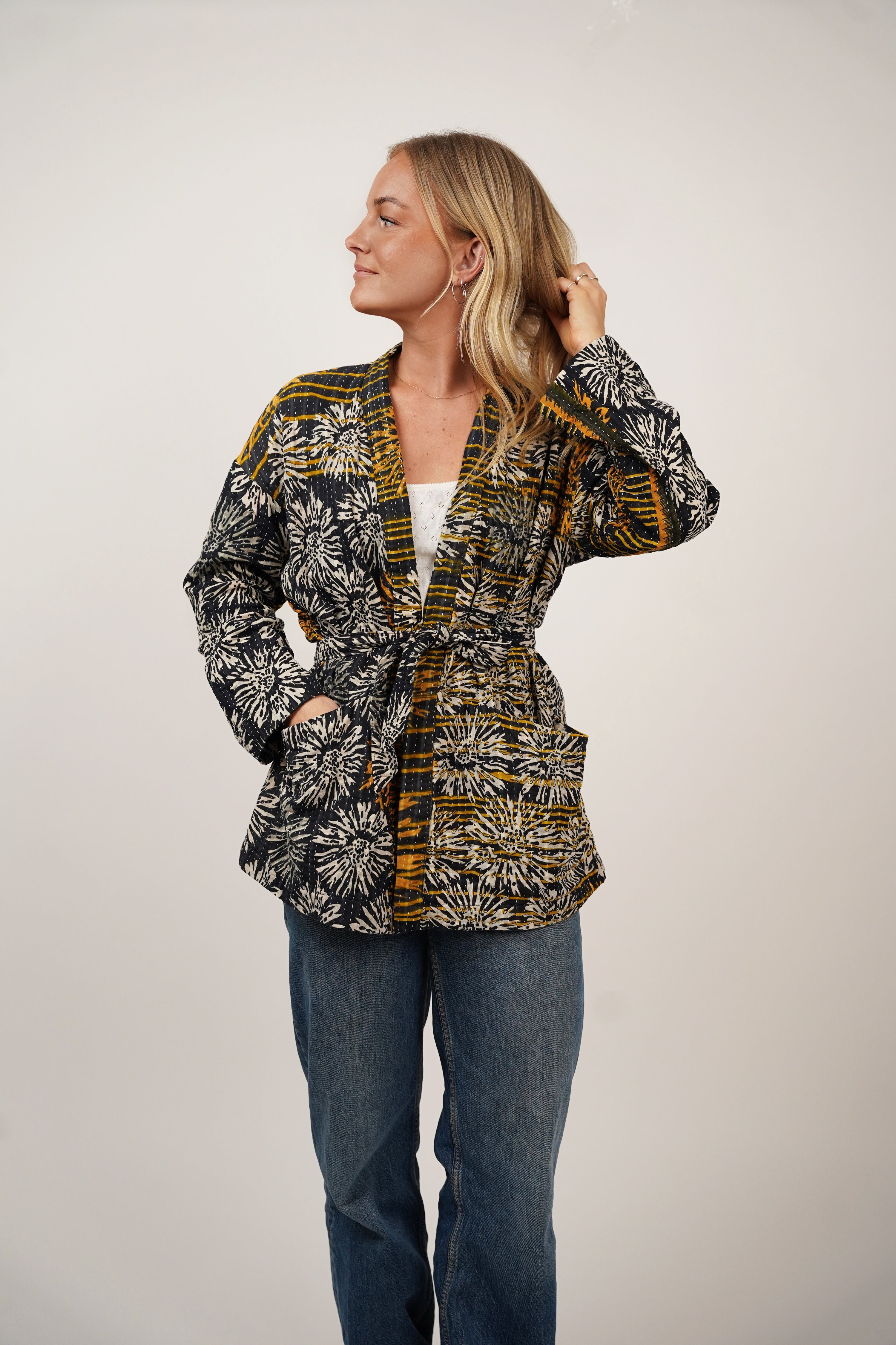 Woman wearing the Komi Jacket sewing pattern from Wardrobe by Me on The Fold Line. An unlined jacket pattern made in cotton, linen, double gauze, quilted, or jersey fabric, featuring a wrap front with a belt, dropped shoulders, and deep pockets.
