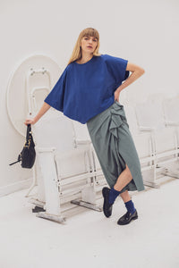 Woman wearing the Kornelia T-shirt sewing pattern from Fibre Mood on The Fold Line. A top pattern made in jersey fabric, featuring an oversized silhouette, round neckline, and asymmetrical design with one short sleeve and one mid-length sleeve.