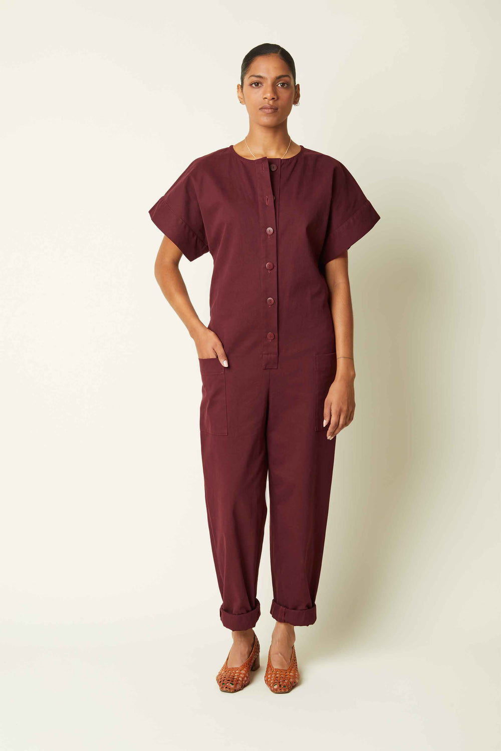 Woman wearing the La Combinaison sewing pattern from Atelier Brunette on The Fold Line. A jumpsuit pattern made in linen, cotton, cotton-linen, linen-viscose, corduroy, or cotton double gauze fabric, featuring a front button placket, wide short sleeves, elasticated back waist, and patch pockets at the sides.