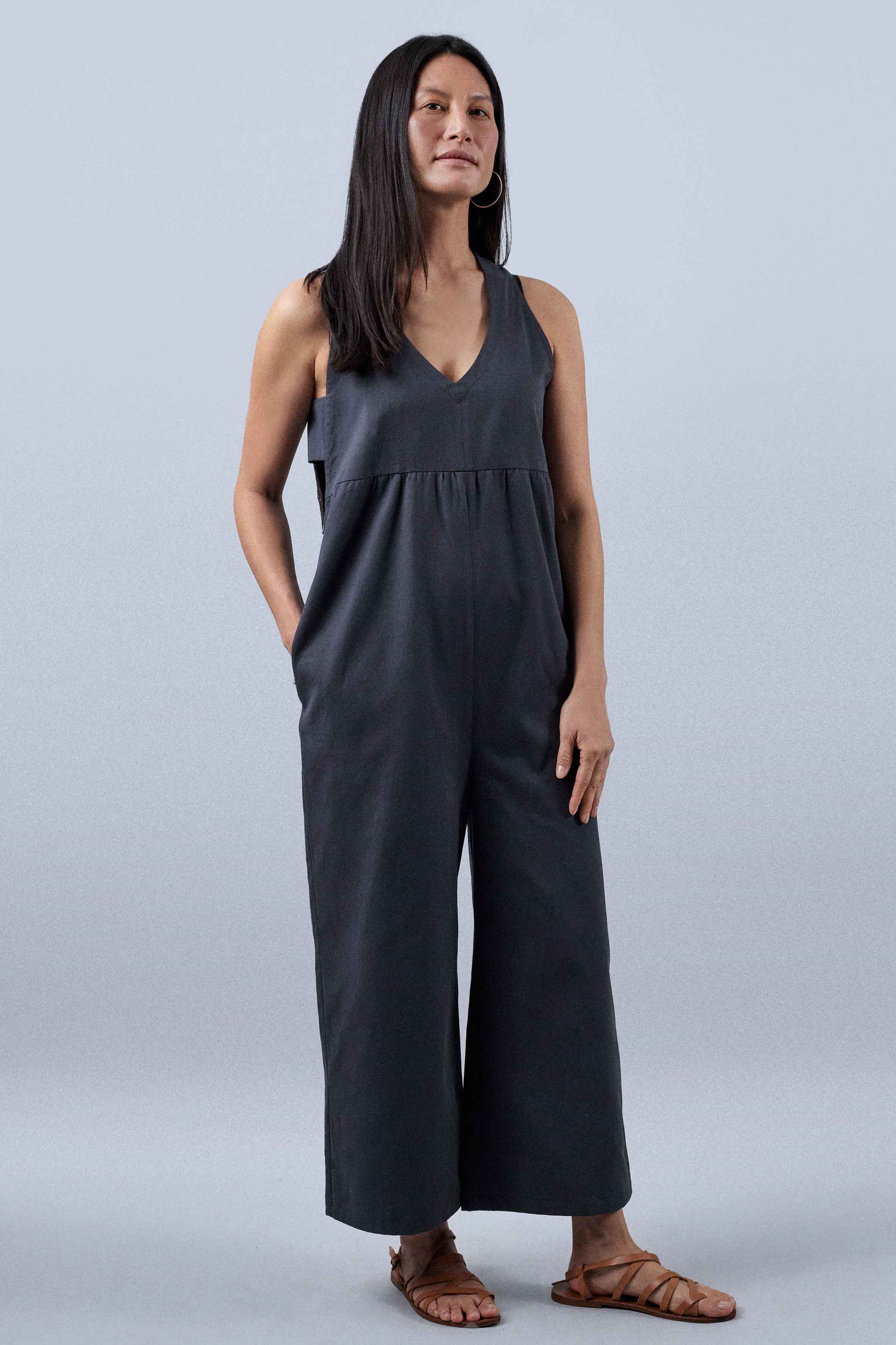 Woman wearing the La Combishort sewing pattern from Atelier Brunette on The Fold Line. A jumpsuit pattern made in rayon, linen, lightweight gabardine, or tencel fabric, featuring a V-neck, wide straps, side panels, and side seam pockets.
