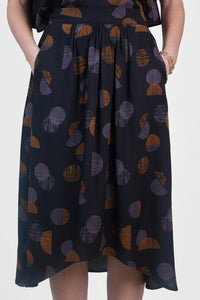 Woman wearing the La Jupe Déroutante sewing pattern from Atelier Brunette on The Fold Line. A skirt pattern made in viscose or viscose blend, linen, or lightweight cotton blend fabric, featuring gathers at the front, a gathered elastic waistband at the back, side pockets, and a high-low hemline.