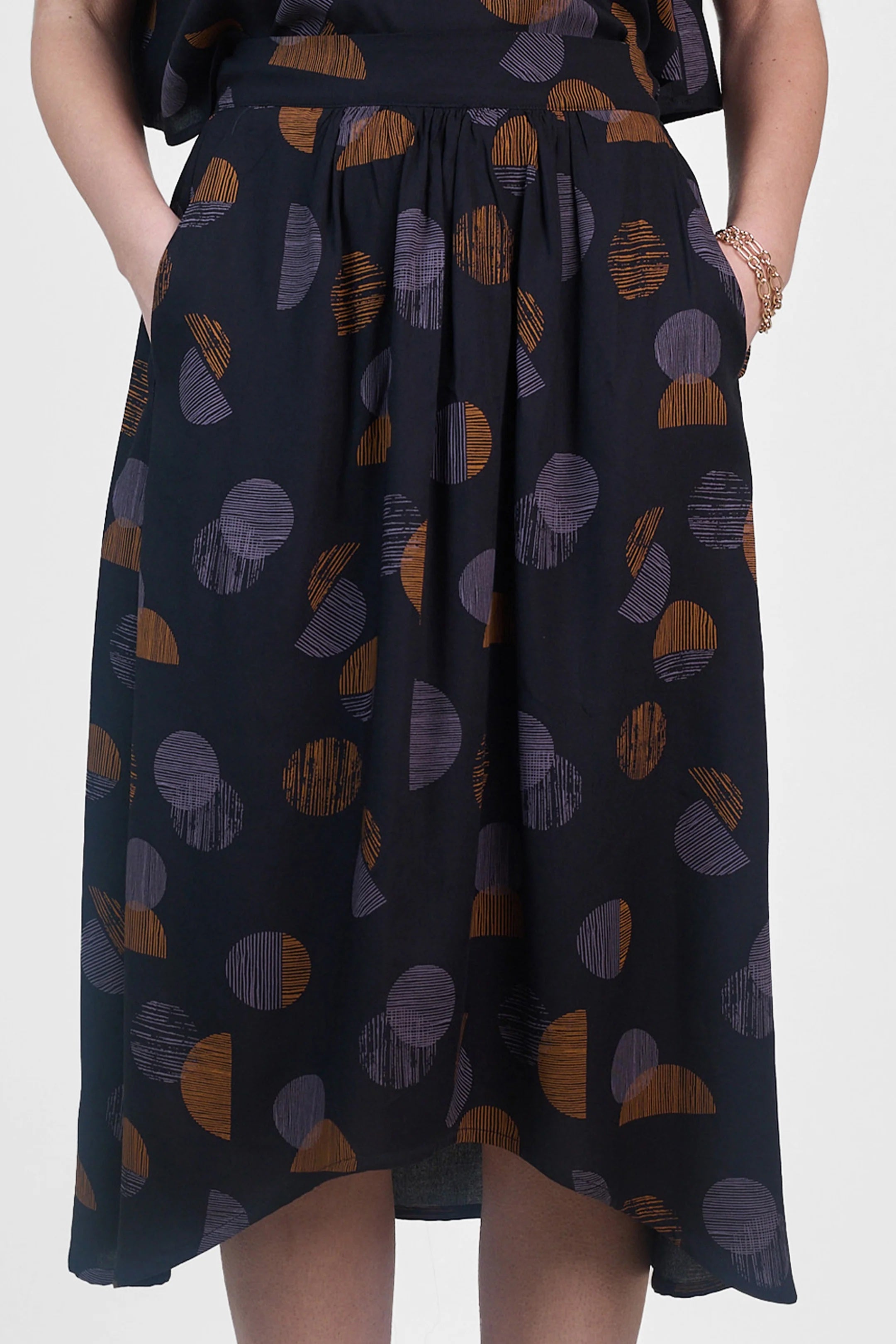 Woman wearing the La Jupe Déroutante sewing pattern from Atelier Brunette on The Fold Line. A skirt pattern made in viscose or viscose blend, linen, or lightweight cotton blend fabric, featuring gathers at the front, a gathered elastic waistband at the back, side pockets, and a high-low hemline.