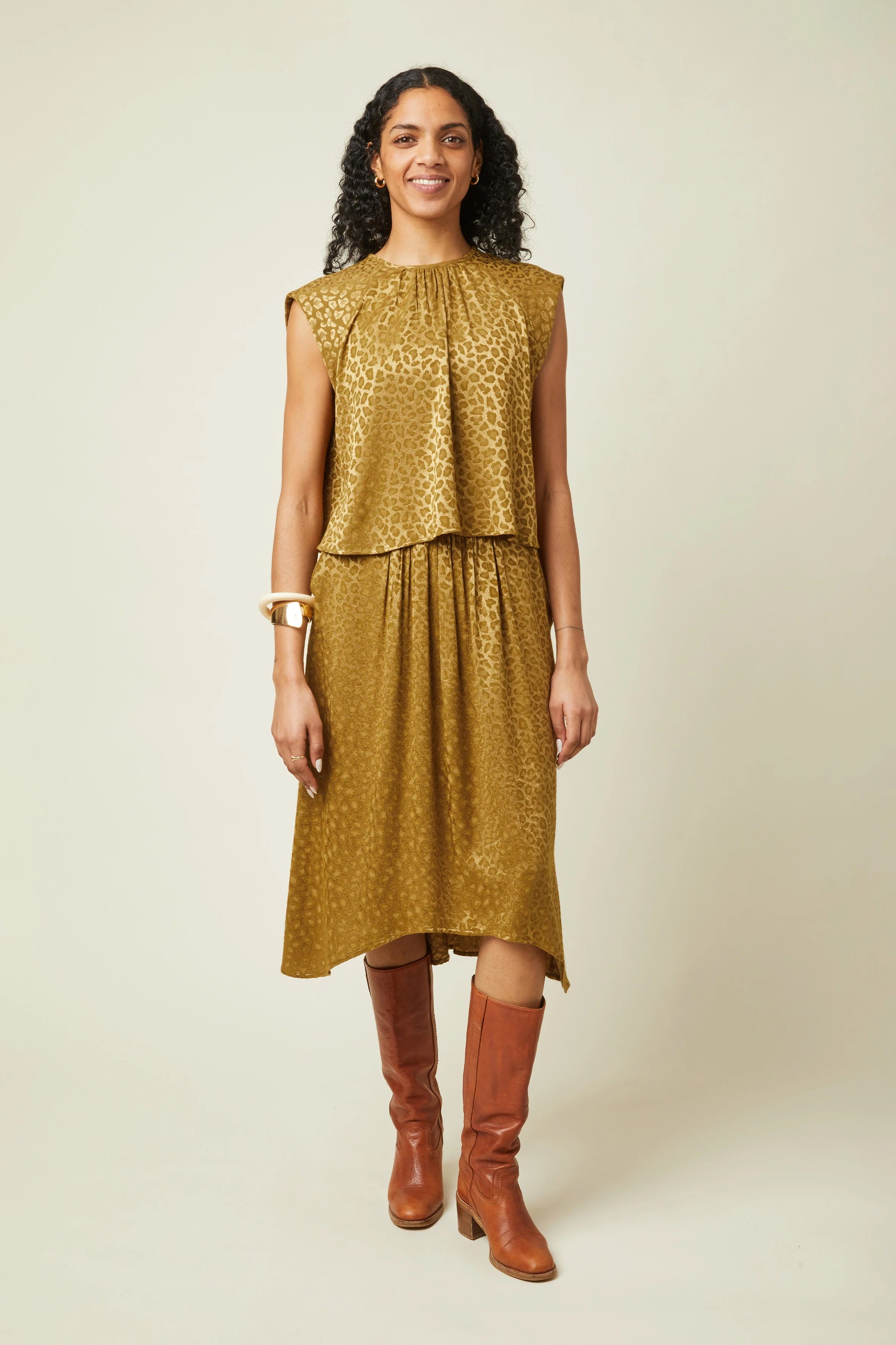 Woman wearing the La Jupe Déroutante sewing pattern from Atelier Brunette on The Fold Line. A skirt pattern made in viscose or viscose blend, linen, or lightweight cotton blend fabric, featuring gathers at the front, a gathered elastic waistband at the back, side pockets, high-low hemline, and knee length.