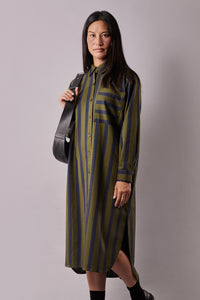 Woman wearing the La Robe Chemise sewing pattern from Atelier Brunette on The Fold Line. A shirt dress pattern made in cotton, viscose, or linen fabric, featuring a relaxed fit, shirt collar, front button placket, chest pocket, back yoke with gathers, long sleeves with cuffs, side slits, and midi length.