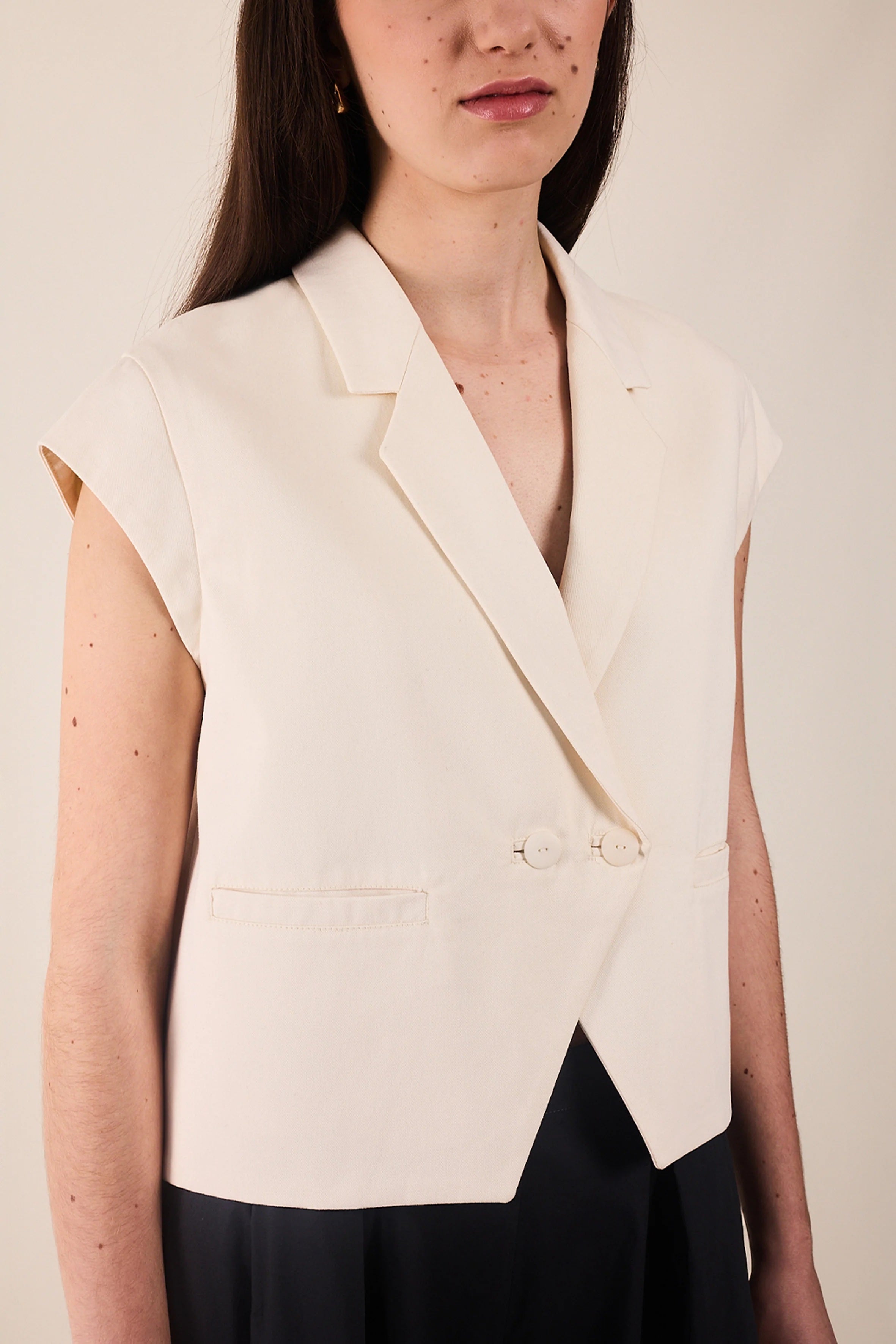 Woman wearing the La Veste Spencer sewing pattern from Atelier Brunette on The Fold Line. A lined blazer pattern made in corduroy, gabardine, linen or linen blend fabric, featuring a slightly flared cut, tailored collar, cap sleeves, double-breasted button closure, and welt pockets.