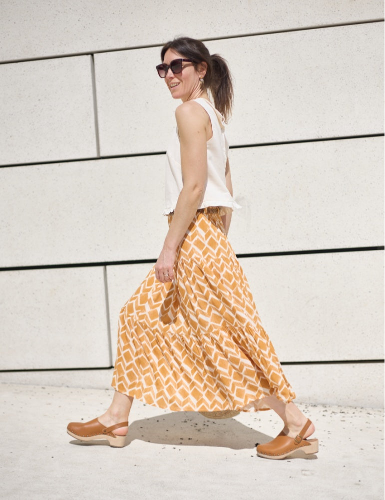 Woman wearing the Lagune Skirt sewing pattern from Atelier Scämmit on The Fold Line. A skirt pattern made in silk, viscose, or linen fabric, featuring an elastic waist, gathered tiers, and midi length.