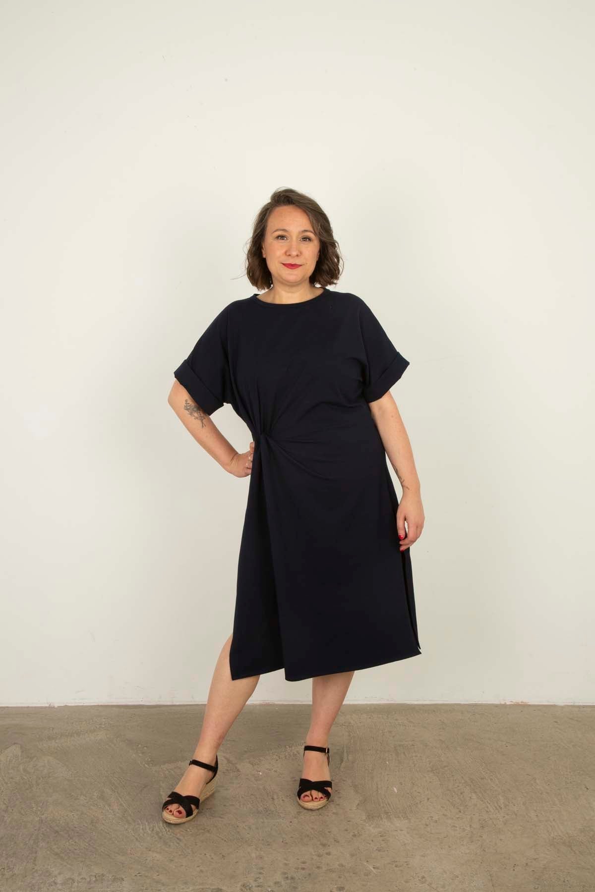 Woman wearing the Layla Dress sewing pattern from Sew Over It on The Fold Line. A dress pattern made in knit fabric, featuring a relaxed fit, round neckline, grown-on short sleeves with cuffs, twist at the waist, side splits, and below knee length.