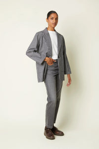 Woman wearing the Le Blazer sewing pattern from Atelier Brunette on The Fold Line. An unlined blazer pattern made in gabardine, cotton-linen twill, or jacquard fabric, featuring a slightly oversized cut, tailored collar, single button closure, and patch pockets.