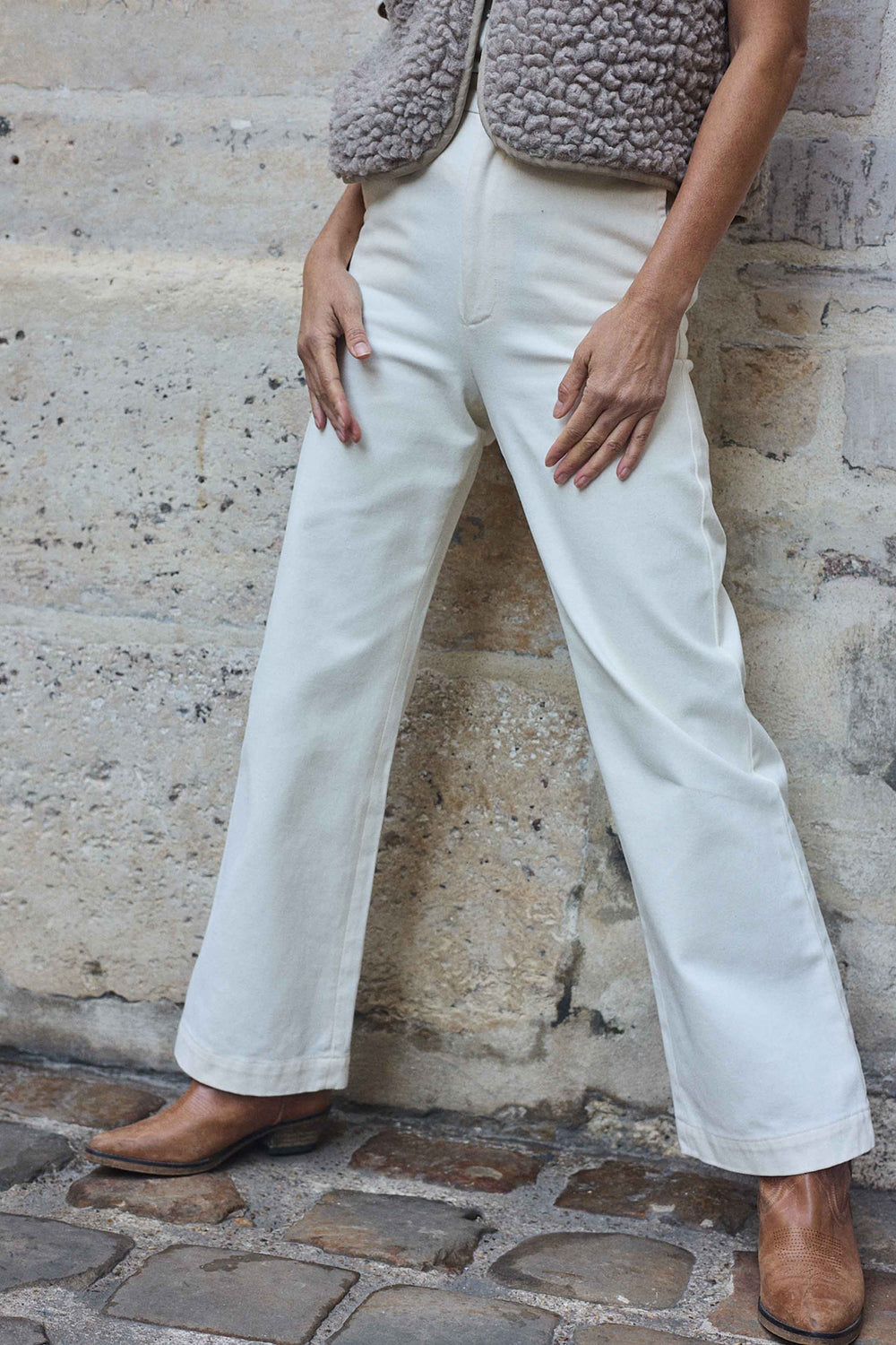 Woman wearing the Le Pantalon sewing pattern from Atelier Brunette on The Fold Line. A bootcut trousers pattern made in gabardine, corduroy, or velvet fabric, featuring a high waist, waistband with belt loops, fly front zipper, side pockets, and back welt pockets.