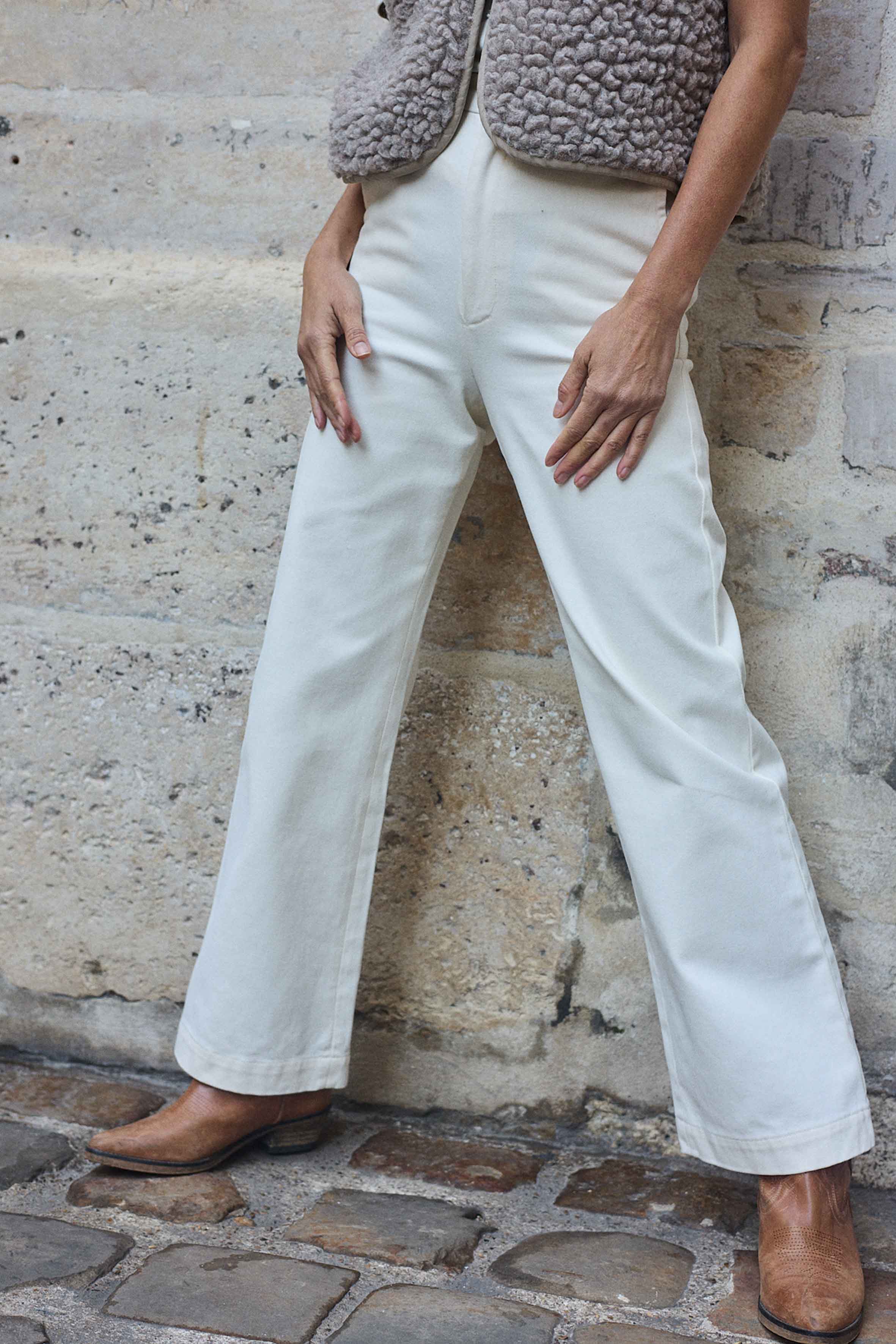 Woman wearing the Le Pantalon sewing pattern from Atelier Brunette on The Fold Line. A bootcut trousers pattern made in gabardine, corduroy, or velvet fabric, featuring a high waist, waistband with belt loops, fly front zipper, side pockets, and back welt pockets.