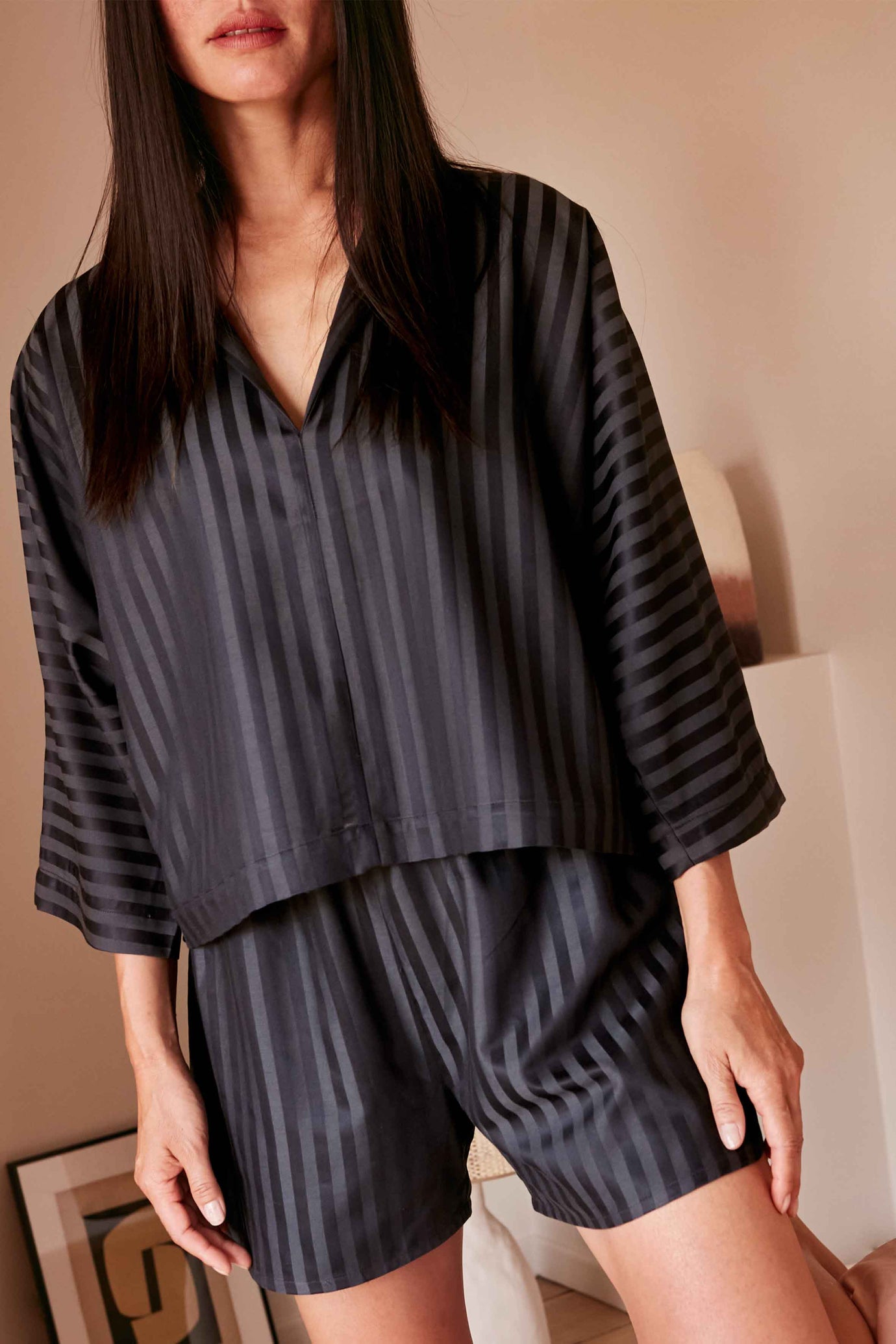 Woman wearing the Le Pyjama sewing pattern from Atelier Brunette on The Fold Line. A pyjamas pattern made in cotton-viscose, viscose, cotton, cotton double gauze, cotton gauze, linen-viscose, or linen-cotton fabric, featuring a top with a notched collar and grown-on sleeves and shorts with an elasticated waistband and rounded sides.