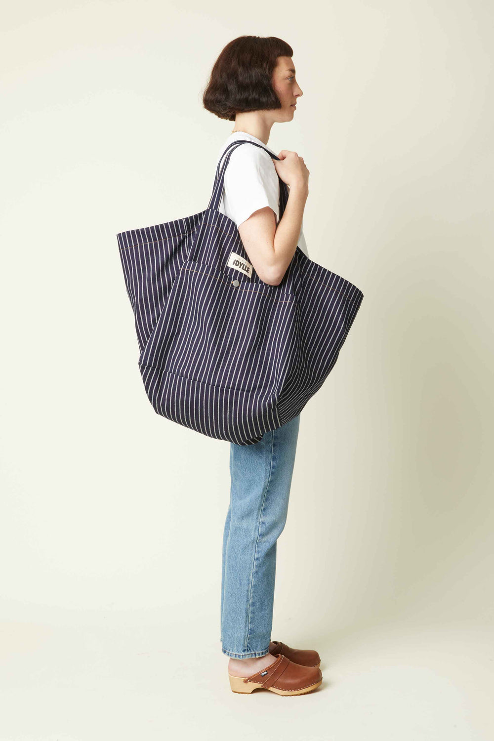 Woman carrying the Le Sac de Plage sewing pattern from Atelier Brunette on The Fold Line. An extra large tote bag pattern made in gabardine, cotton canvas, linen, or a quilted fabric, featuring a large front pocket.