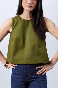 Woman wearing the Le Top sewing pattern from Atelier Brunette on The Fold Line. A sleeveless top pattern made in lightweight gabardine, linen, or cotton fabric, featuring a trapeze shape, round neckline, back invisible zip, and buttons at the sides.