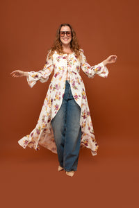 Woman wearing the Lexee Corset Dress sewing pattern from Madalynne on The Fold Line. A dress pattern made in cotton voile, cotton lawn, cotton batiste, cotton gauze, chambray, or linen fabric, featuring a lace-up front bodice, long sleeves with bell cuffs, open-front skirt, and maxi length.