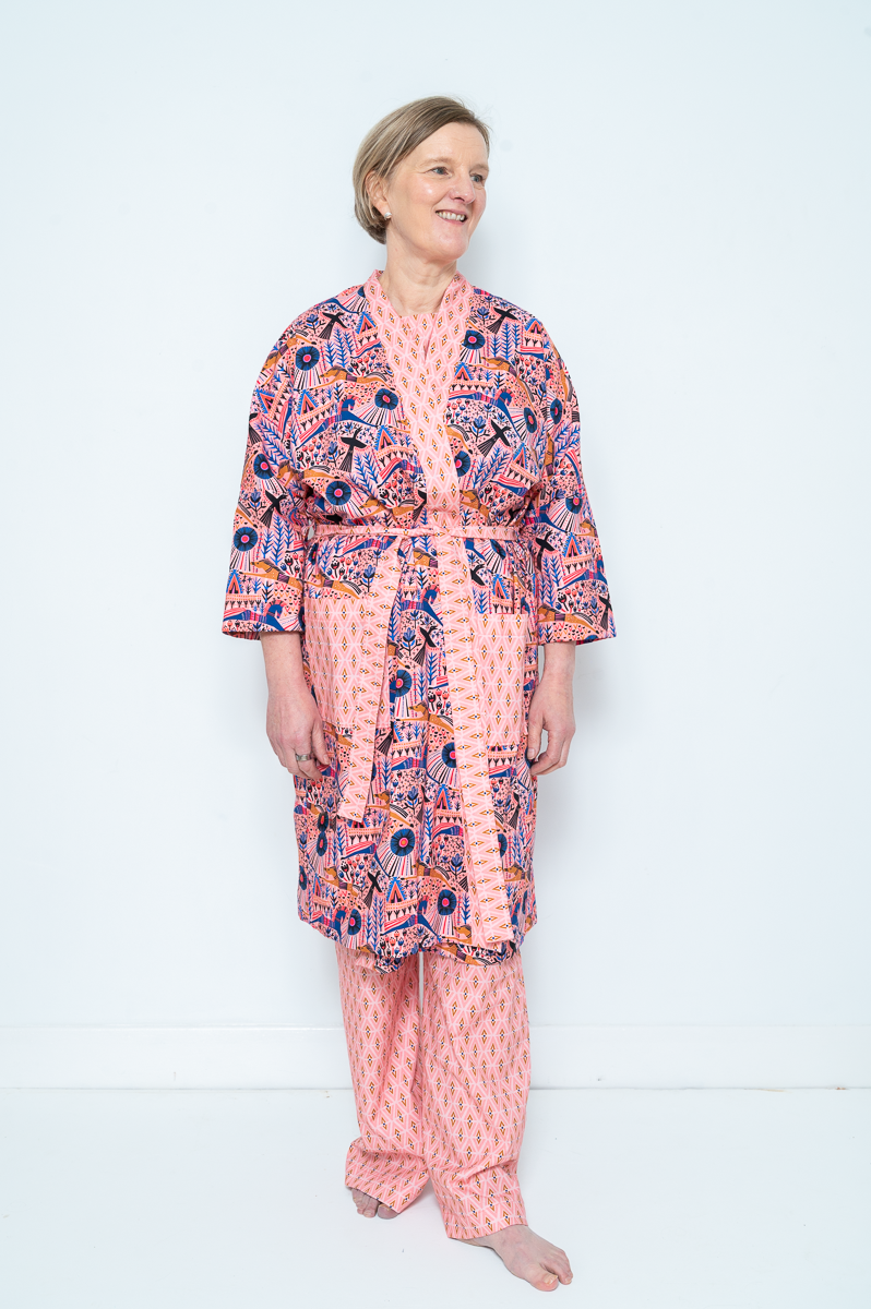 Woman wearing the Lorna Dressing Gown sewing pattern from Bobbins and Buttons on The Fold Line. A dressing gown pattern made in craft weight cotton, chambray, cotton lawn, cotton blends, linen, stable knits, cotton waffle, or cotton jacquard fabric, featuring a relaxed fit, front facing band, patch pockets, and tie belt.
