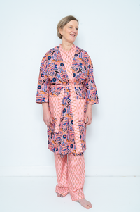 Woman wearing the Lorna Dressing Gown sewing pattern from Bobbins and Buttons on The Fold Line. A dressing gown pattern made in craft weight cotton, chambray, cotton lawn, cotton blends, linen, stable knits, cotton waffle, or cotton jacquard fabric, featuring a relaxed fit, front facing band, patch pockets, and tie belt.