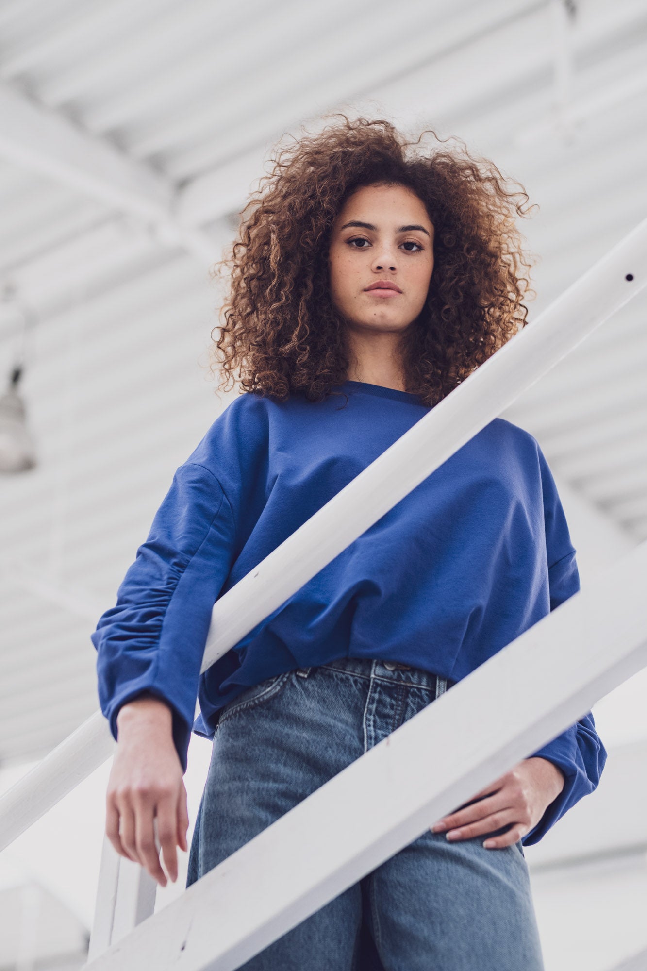 Woman wearing the Lotta Sweater sewing pattern from Fibre Mood on The Fold Line. A top pattern made in French terry, sweatshirt, punta di Roma, or light softshell fabric, featuring a relaxed fit, round neckline, dropped shoulders, gathered long sleeves, and balloon hem.