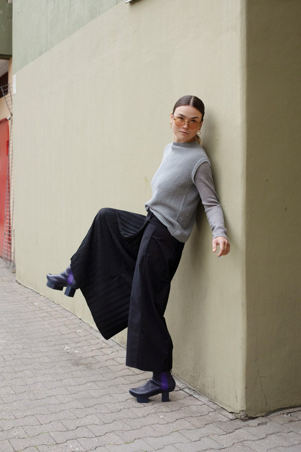 Woman wearing the Luce Trousers sewing pattern from TAUKO on The Fold Line. An asymmetrical trousers pattern made in cotton blends, light wool, or linen fabric, featuring wide legs, side seam pockets, and a press button (snap) closure at the waist.