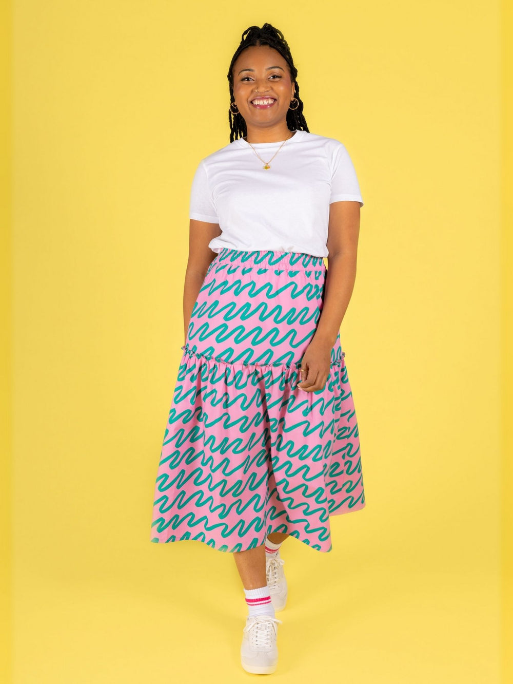 Woman wearing the Luella Skirt sewing pattern from Tilly and the Buttons on The Fold Line. A skirt pattern made in cotton lawn, poplin, double gauze, seersucker, linen blend, viscose (rayon), or crepe fabric, featuring two tiers with an exposed frill seam, elastic waist, pockets, and midi length.