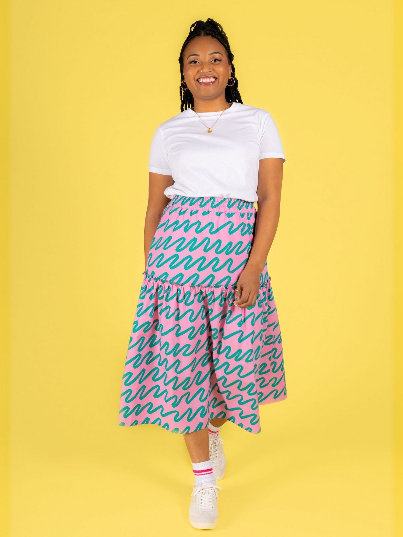Woman wearing the Luella Skirt sewing pattern from Tilly and the Buttons on The Fold Line. A skirt pattern made in cotton lawn, poplin, double gauze, seersucker, linen blend, viscose (rayon), or crepe fabric, featuring two tiers with an exposed frill seam, elastic waist, pockets, and midi length.