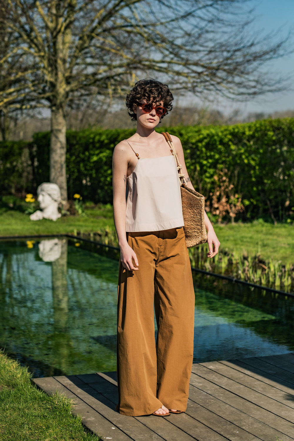 Woman wearing the Luki Trousers sewing pattern from Fibre Mood on The Fold Line. A trousers pattern made in denim, twill, cotton blends, linen blends, or corduroy fabric, featuring a shaped waistband with belt loops, zip fly, front side pockets, back patch pockets, insert in the side seam, and wide leg.