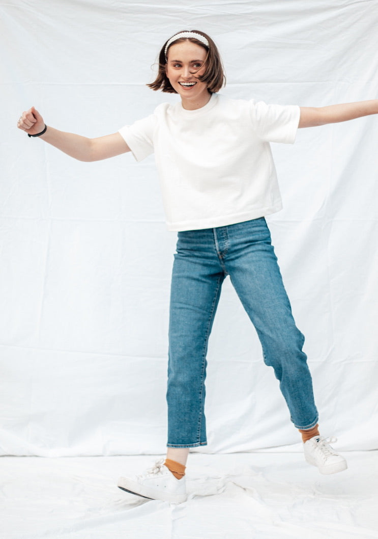Woman wearing the MADE-line Tee sewing pattern from Madswick on The Fold Line. A T-shirt pattern made in knit fabric such as French terry, ponte, rib, jersey, fleece, modal, or waffle fabric, featuring a boxy fit, round neck, slightly dropped shoulders, and short sleeves.