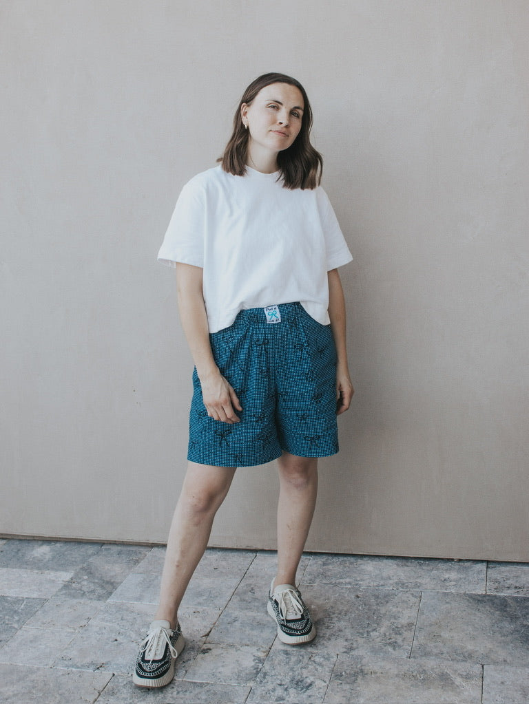 Woman wearing the Madeline Shorts sewing pattern from Madswick on The Fold Line. A shorts pattern made in linen, viscose, tencel, denim, cotton lawn, cotton poplin, quilting cotton, or cotton twill fabric, featuring a grown-on elastic waistband, wide legs, and in-seam pockets.