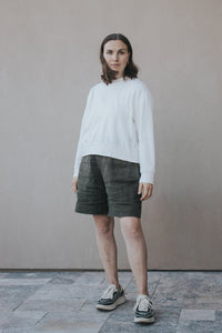 Woman wearing the Madeline Sweatshirt sewing pattern from Madswick on The Fold Line. A sweatshirt pattern made in knit fabric such as French terry, ponte, rib, jersey, fleece, modal, or waffle fabric, featuring a round neck, slightly dropped shoulders, long sleeves with wrist cuffs, and a wide hem band.