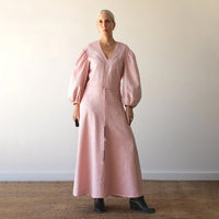 Woman wearing the Magda Dress sewing pattern from Pattern Fantastique on The Fold Line. A dress pattern made in linen, cotton, lighter corduroy, or denim fabric, featuring a V-neckline, bust and skirt yokes, voluminous long sleeves, drawstring waist, and maxi length.